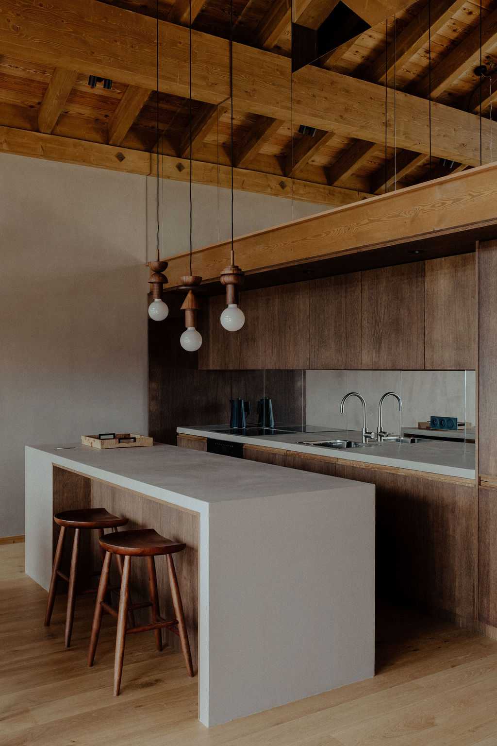 Cuisine en bois avec îlot central et suspensions dans un chalet aménagé par un architecte d'intérieur à Manigod