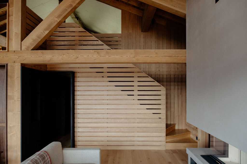 Escalier du chalet menant à la mezzanine derrière un claustra ajouré eb bois 