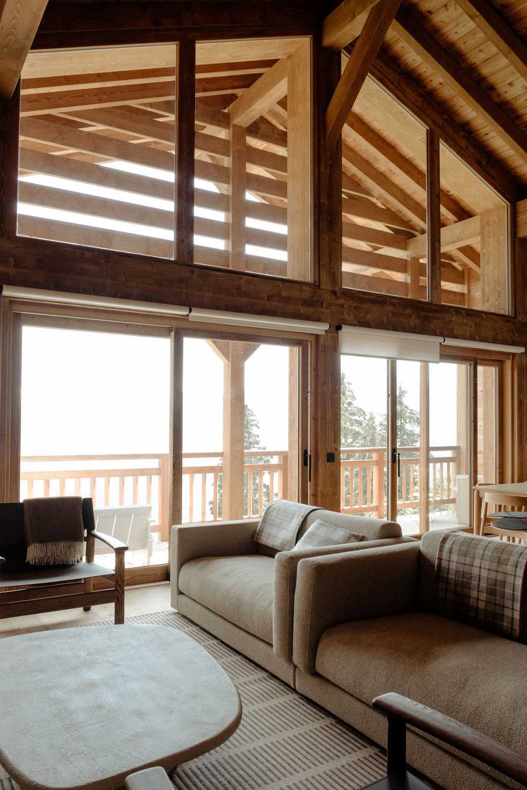 Salon d'un chalet avec des baies vitrées donnant sur le balcon