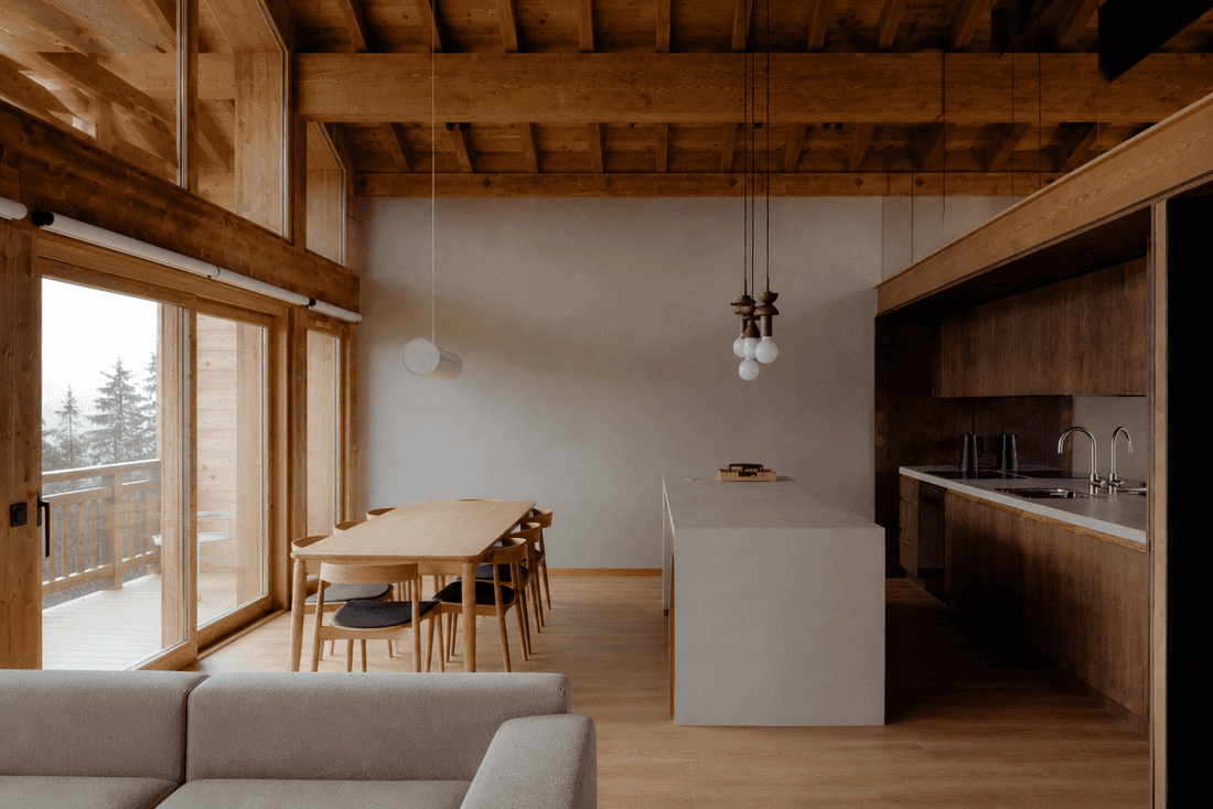 Salle à manger et cuisine ouverte sous la charpente en bois d'un chalet à Annecy