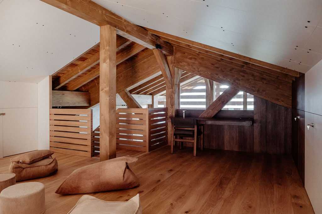 Mezzanine sous combles avec poufs et coussins au sol dans un chalet